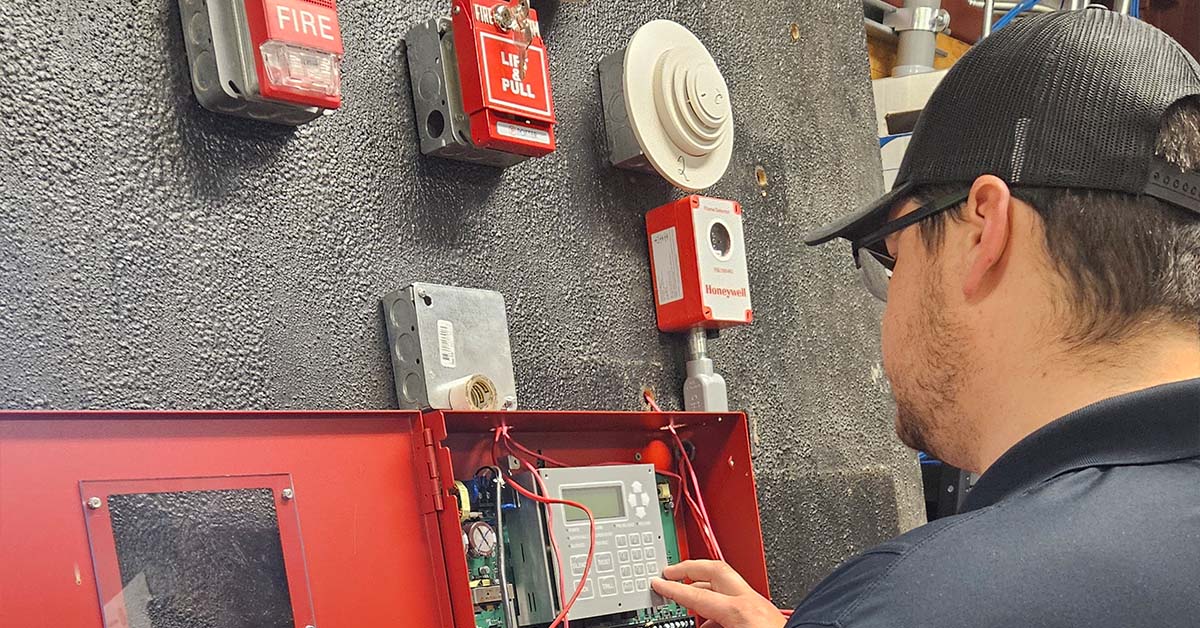 worker testing fire alarms and smoke detectors